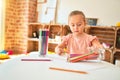 Beautiful blond toddler girl drawing with colored pencils at kindergarten Royalty Free Stock Photo