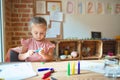 Beautiful blond toddler girl drawing with colored pencils at kindergarten Royalty Free Stock Photo