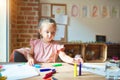 Beautiful blond toddler girl drawing with colored pencils at kindergarten Royalty Free Stock Photo