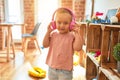 Beautiful blond toddler girl listening to music using headphones at kindergarten Royalty Free Stock Photo