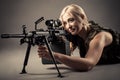 Beautiful blond woman aiming machine gun while lying on the floor Royalty Free Stock Photo