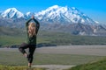 Beautiful blond woman does a yoga pose in front of Denali Mountain in Alaska
