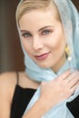 A beautiful blond woman with a glittery blue scarf and black dress.