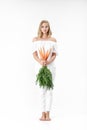 Beautiful blond woman holding fresh carrot with green leaves on white background. Health and Diet Royalty Free Stock Photo