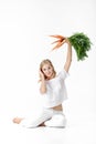 Beautiful blond woman holding fresh carrot with green leaves on white background. Health and Diet Royalty Free Stock Photo