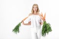 Beautiful blond woman holding fresh carrot with green leaves on white background. Health and Diet Royalty Free Stock Photo