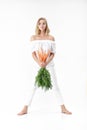 Beautiful blond woman holding fresh carrot with green leaves on white background. Health and Diet Royalty Free Stock Photo