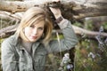 A beautiful blond woman holding onto a tree limb while sitting amonst flowers. Royalty Free Stock Photo