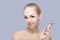 Beautiful blond woman holding pink lip gloss on gray background. lip makeup Royalty Free Stock Photo