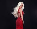 Beautiful blond woman in red dress isolated on black background.