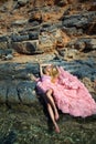 Beautiful blond woman pink ballroom dress standing on the rocks in Santorini Royalty Free Stock Photo