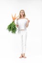 Beautiful blond woman showing rabbit and holding fresh carrot with green leaves on white background. Health and Diet Royalty Free Stock Photo