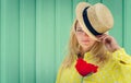 Beautiful blond woman in straw hat holding a red flower