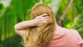 Beautiful blond woman touches her hair in nature. back view. hair treatment concept