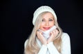 Beautiful blond woman in white, knitted hat and scarf. On a black background. Royalty Free Stock Photo