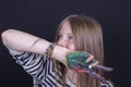 Beautiful blond young girl with freckles and hands painted in colorful paints indoors on black background, closeup portrait Royalty Free Stock Photo