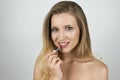 Beautiful blond young smiling woman putting lipstick on close up isolated white background Royalty Free Stock Photo