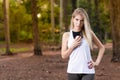 Beautiful blond young woman in park at sunset holding mobile near chest - Image