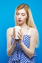 Beautiful Blonde with Bare Shoulders Wearing Striped Dress is Holding White Candle in Her Hands and Looking on it