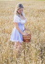 Blonde with a basket tears wheat in the field