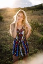 Beautiful blonde with beautiful eyes in blue overalls in nature, sunset sun Royalty Free Stock Photo