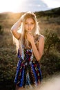 Beautiful blonde with beautiful eyes in blue overalls in nature, sunset sun Royalty Free Stock Photo