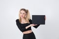 A beautiful blonde in black clothes holds a sheet of black paper in her hands.