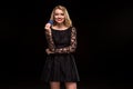 Beautiful blonde in a black dress with casino chips in hands isolated on a black background Royalty Free Stock Photo