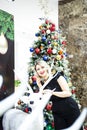 Beautiful blonde in a black dress hugs the figure of a deer near the Christmas tree Royalty Free Stock Photo