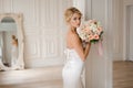 Beautiful blonde bride in the elegant white dress holding a wedding bouquet Royalty Free Stock Photo