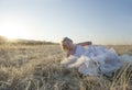 Beautiful blonde bride posing in frosty field at sunrise Royalty Free Stock Photo