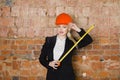 Beautiful blonde businesswoman with application tier at loft office in orange construction helmet and suit. Royalty Free Stock Photo