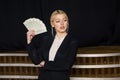 Beautiful blonde businesswoman with money at loft office in black suit. Royalty Free Stock Photo