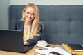 Beautiful blonde businesswoman is sitting on sofa and surfing on internet at cafe Royalty Free Stock Photo