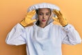 Beautiful blonde caucasian woman wearing protective beekeeper uniform with hand on head for pain in head because stress