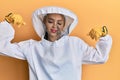 Beautiful blonde caucasian woman wearing protective beekeeper uniform showing arms muscles smiling proud