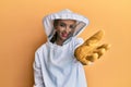 Beautiful blonde caucasian woman wearing protective beekeeper uniform smiling friendly offering handshake as greeting and