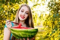 Beautiful blonde girl in blue dress eating a watermelon outdoors Royalty Free Stock Photo