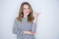 Beautiful blonde girl with blue eyes wearing striped sweater over white isolated background smiling with happy face looking and Royalty Free Stock Photo