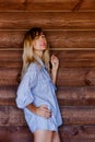 Beautiful blonde girl in men`s shirt on the background of wooden wall Royalty Free Stock Photo