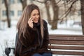 beautiful blonde girl Caucasian appearance in a fur coat sitting in a Park on a bench in the winter and talking on the Royalty Free Stock Photo