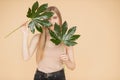 Beautiful blonde girl with clean skin holds green leaf on beige background. Beauty spa care cream concept Royalty Free Stock Photo