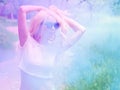 Beautiful blonde girl dancing in a multi-colored smoke outdoors in the forest. blue purple smoke. Portrait. The concept of leisure Royalty Free Stock Photo