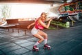 Beautiful blonde girl is doing some tricks during rollerblading. She is standing in a squat position and looking down Royalty Free Stock Photo