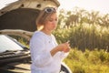 Beautiful blonde girl is engaged in repairing a car on a country road and holds a wrench and spark plugs in the rayst Royalty Free Stock Photo