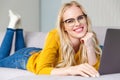 beautiful blonde girl in eyeglasses using laptop and smiling Royalty Free Stock Photo