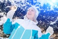 Beautiful blonde girl with a glass of champagne sings and dances outdoors on a background of snowy fir-trees in winter Royalty Free Stock Photo