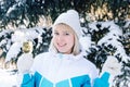 Beautiful blonde girl with a glass of champagne sings and dances outdoors on a background of snowy fir-trees in winter Royalty Free Stock Photo