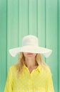 Beautiful blonde girl hiding behind hats fields