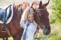 Beautiful blonde girl hugging her brown horse. Summer photo in warm tones.